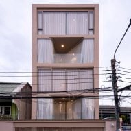 Curving glass walls puncture pink-toned house in Thailand